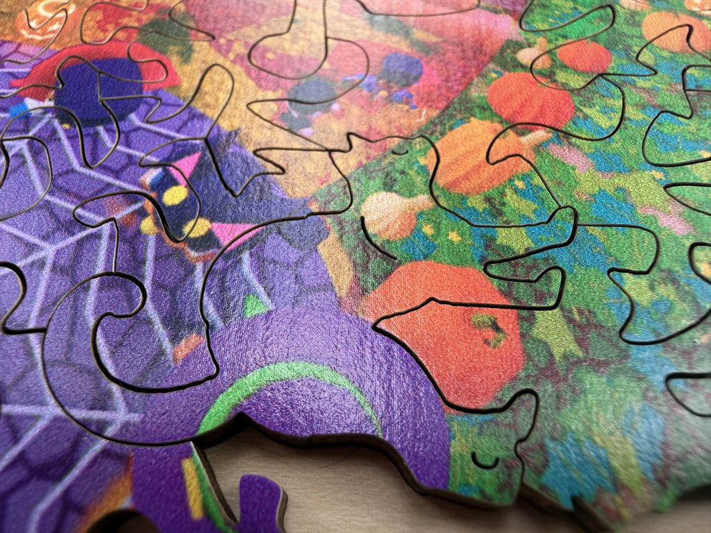 Low-angle detail of the puzzle edge, showing the thick wooden pieces, cauldron, spider web, and pumpkin patch artwork