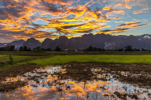 Fire Over Still Water — orange sunset clouds reflected in a paddy field near Vang Vieng, Laos
